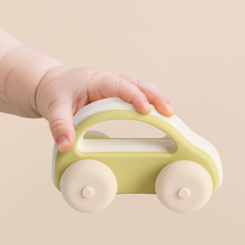 Vaiko rankytė laiko žalia silikoninį automobiliuka
