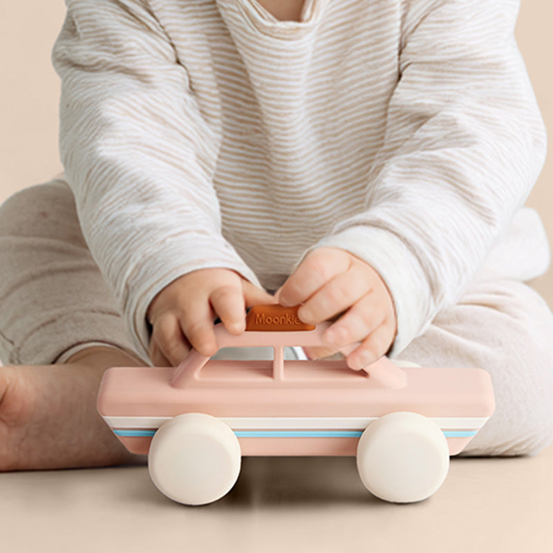 Vaikas laiko rožini silikonini automobiliuką